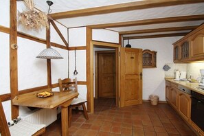 A rustic kitchen with wooden beams, a dining table with chairs, and a hanging lamp. - Holiday apartment with 1 bedroom (Zell \/ Mosel)