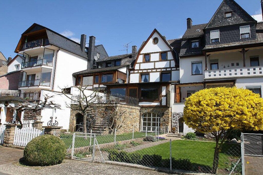 A row of traditional European-style houses with stone foundations, wooden balconies, and a well-maintained lawn.