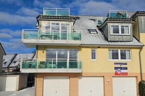 Ein zweistöckiges Gebäude mit Balkon, großen Fenstern und einer Garage.