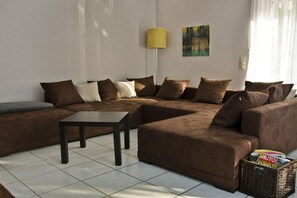 A living room with a sectional sofa, a coffee table, a floor lamp, and a painting on the wall.