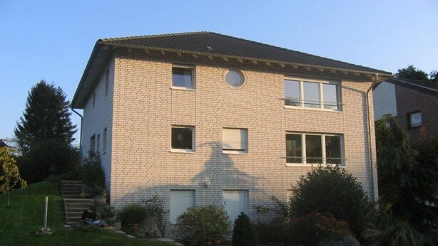 A two-story residential building with a brick facade, multiple windows, and a small front yard with landscaping. - Holiday apartment with 1 bedroom (Eschweiler)