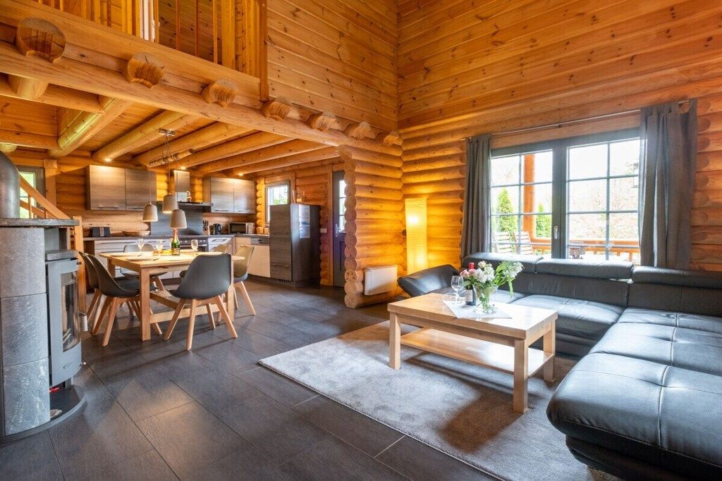 A log cabin interior with a dining area, kitchen, and living space.