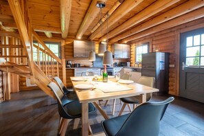 Ein Holzblockhaus-Innenraum mit Essbereich, Küche und Treppe.