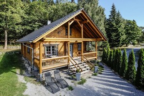 Eine Blockhütte mit Veranda, Treppe und einem Schotterweg.