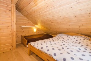 Ein Zimmer mit Holzboden, einem Bett, einer Bank und einer Lampe.
