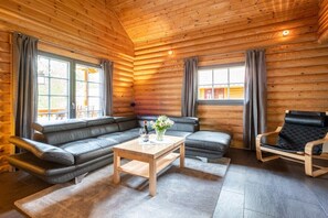 Ein gemütliches Blockhaus-Interieur mit einer Couch, einem Holztisch und einem Ledersessel.