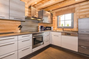 A modern kitchen with stainless steel appliances, wooden cabinetry, and a window providing natural light. - Holiday home in Schierke with sauna (Schierke)