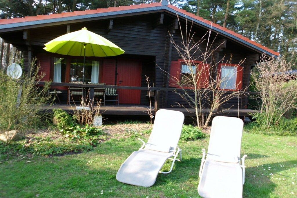 Een blokhut met twee lounge fauteuils en een groene parasol.