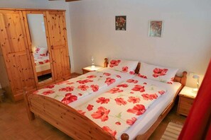 Ein Schlafzimmer mit einem hölzernen Bett, zwei Nachttischen, einem Schrank und einem Spiegel.