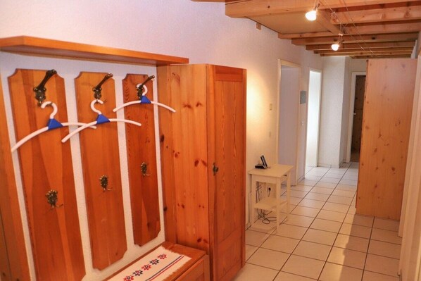 Une armoire en bois avec plusieurs cintres et une petite table accompagnée d’une chaise.