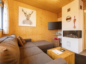 Un salon chaleureux avec un canapé, un téléviseur à écran plat, une cheminée et un mur en bois.