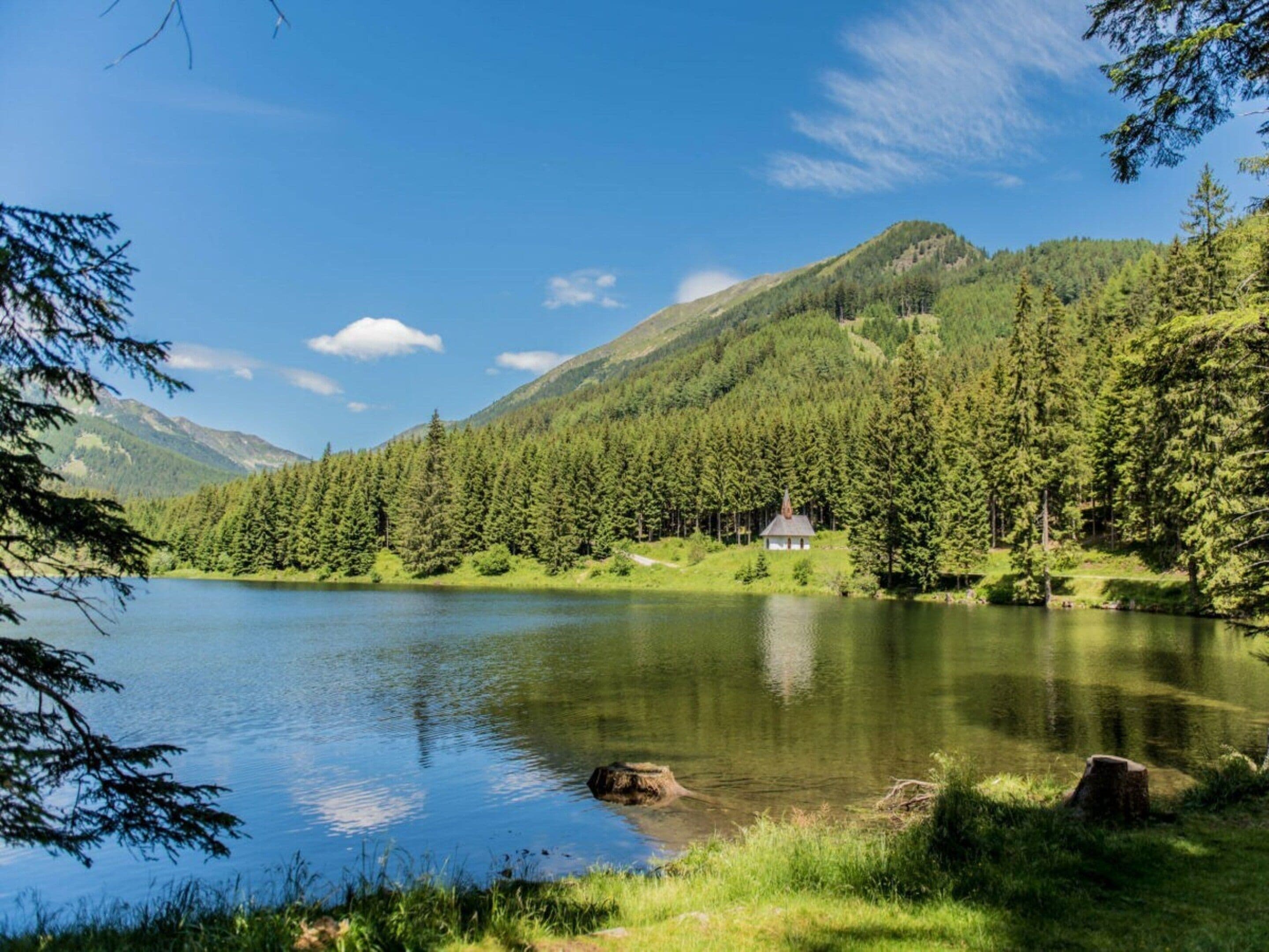 A serene lake surrounded by dense forest and mountains.