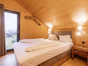 Une chambre dans une cabane en bois, avec un lit, une table de chevet et une fenêtre.