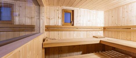 Una sauna de madera con bancos y un ventanal pequeño.