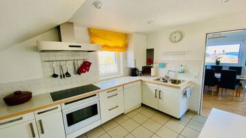 A kitchen with white cabinets, a stove, a sink, and a window with yellow curtains.