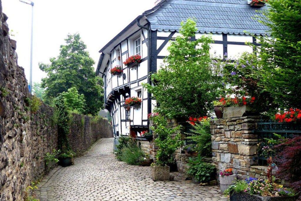 A traditional half-timbered building with a cobblestone alley, stone walls, and flower boxes.