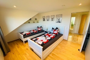 Ein Schlafzimmer mit zwei Betten, Holzboden und schräg verlaufender Decke.