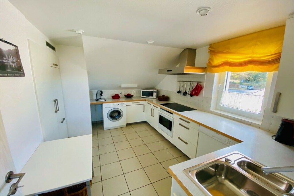 A compact kitchen with a washing machine, a microwave, and a sink.