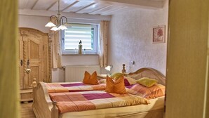 A bedroom with a wooden bed, a window with blinds, a radiator, and a wall-mounted picture. - Holiday apartment in Mauth with sauna (Mauth)