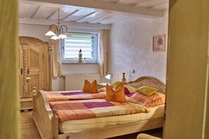 A bedroom with a wooden bed, a window with blinds, a radiator, and a wall-mounted picture. - Holiday apartment in Mauth with sauna (Mauth)