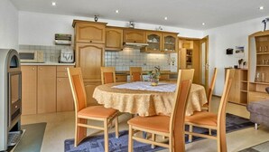 A compact kitchen with wooden cabinets, a dining table with chairs, and a built-in microwave. - Holiday apartment in Mauth with sauna (Mauth)