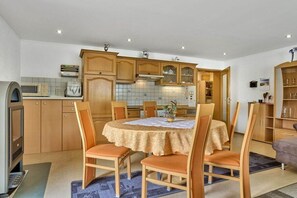 A compact kitchen with wooden cabinets, a dining table with chairs, and a built-in microwave. - Holiday apartment in Mauth with sauna (Mauth)