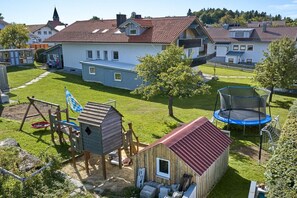 A residential area with a well-maintained lawn, a swing set, a trampoline, and a small wooden structure. - Holiday apartment in Mauth with sauna (Mauth)
