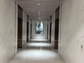 A corridor with a modern design, featuring a central light fixture and a large abstract painting on the wall. - New Apt in Queens Wharf lv21 with Sofa bed (Brisbane City)