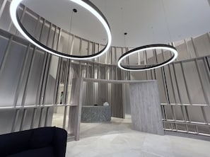 Een modern interieur met een receptiebalie, verticale lamellen en ronde verlichtingsarmaturen.