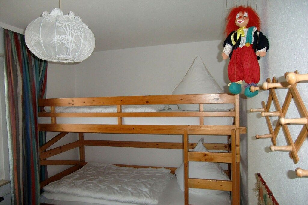 A bunk bed with a hanging toy and a wooden ladder.