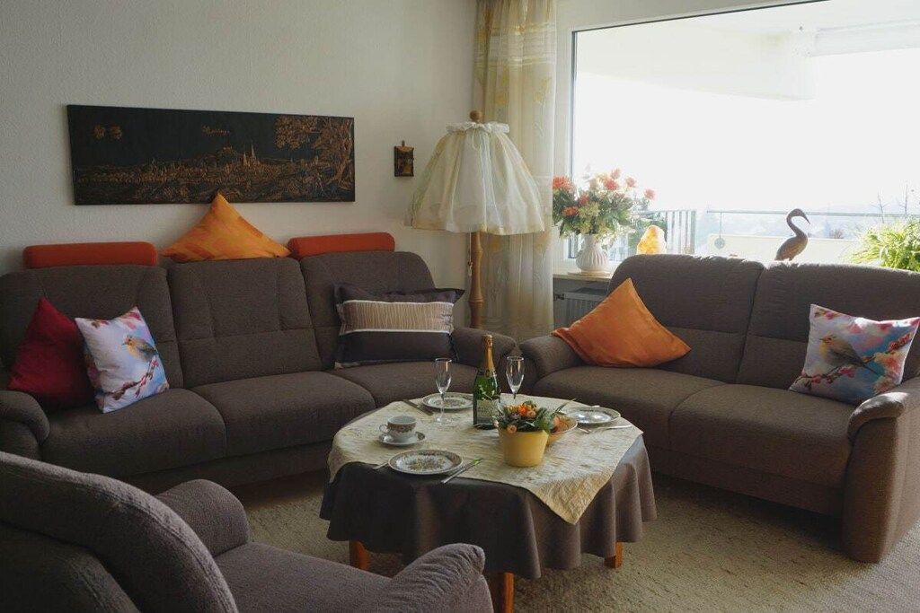 Un salon comprenant un canapé, une table ornée d’un vase de fleurs et une lampe.