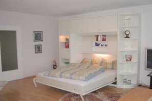 A bedroom with a bed, built-in shelving, and a television. - Döse beach high-rise (Cuxhaven)