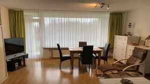 A living room with a TV, dining table, chairs, and a sofa. - Döse beach high-rise (Cuxhaven)
