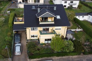 Ein zweistöckiges Haus mit Garage, Balkon und Auffahrt, auf der zwei Autos geparkt sind.