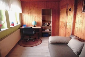 A cozy room with wooden walls, a desk with a globe, a chair, a bookshelf, and a sofa. - Holiday apartment with 2 bedrooms (Frankenfeld)