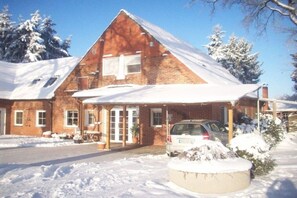 A brick building with a sloped roof, a covered porch, and a car parked in front. - Holiday apartment with 2 bedrooms (Frankenfeld)