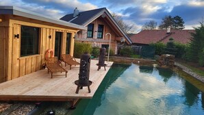 Eine Holzhütte mit Schwimmbad, Sitzgelegenheit im Freien und blauem Himmel.