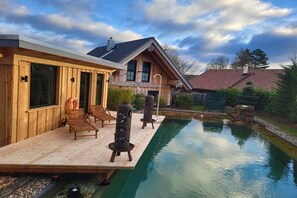 A wooden cabin with a swimming pool, outdoor seating, and a clear sky. - Raccoon Hut Steirer-Hof (Vöhl)