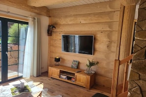 Ein Holzinterieur mit einem an der Wand befestigten Flachbildfernseher, einem Holzkonsole mit einer Lampe und einer Steinwand.