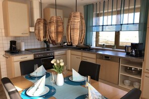 Eine moderne Küche mit Essbereich, ausgestattet mit einem Herd, einer Mikrowelle und einer Kaffeemaschine.