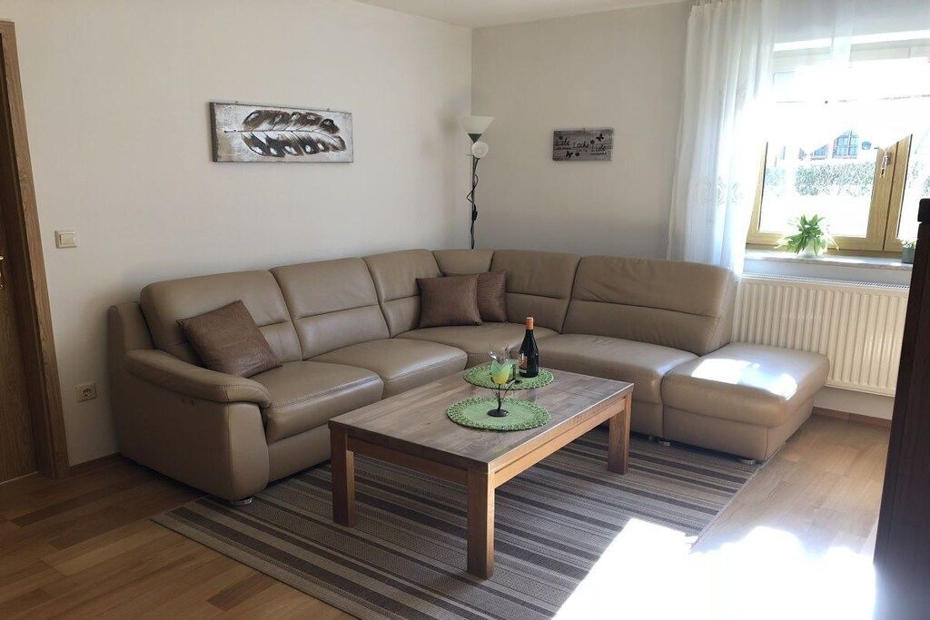 A living room with a beige sectional sofa, a wooden coffee table, and a striped rug.