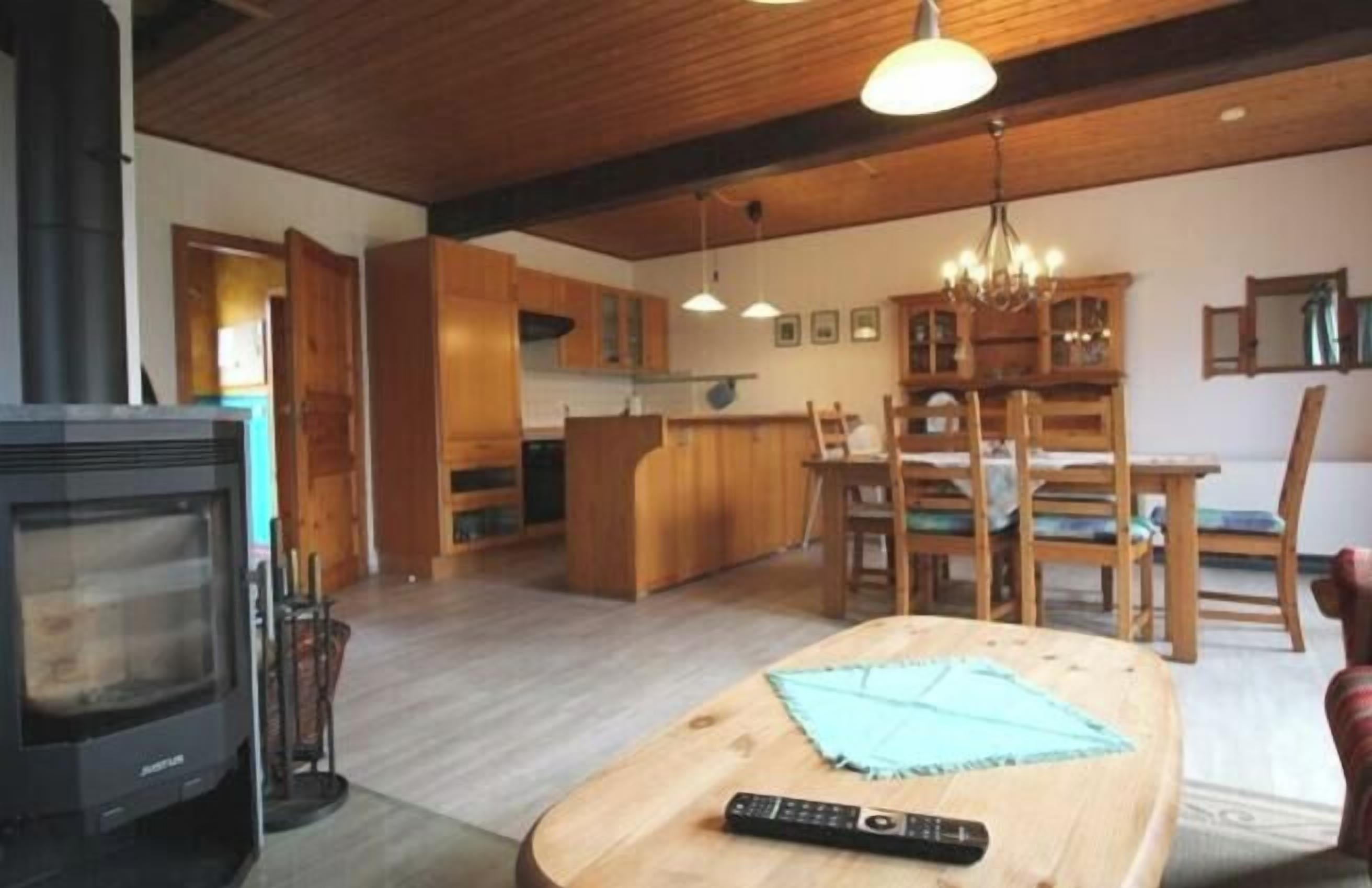 A modern kitchen with wooden cabinets, a dining area with a table and chairs, and a fireplace.