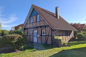 A traditional half-timbered house with a steeply pitched roof, a chimney, and a small front porch. - Gundi's holiday home (Dorum-Neufeld)
