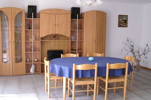 A dining area with a blue tablecloth, wooden chairs, and a cabinet with glass doors. - Holiday home with 3 bedrooms (Wietzendorf)