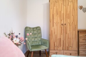 Ein Zimmer mit einem grünen Polsterstuhl, einem Holzschrank und einer kleinen Holzkommode.