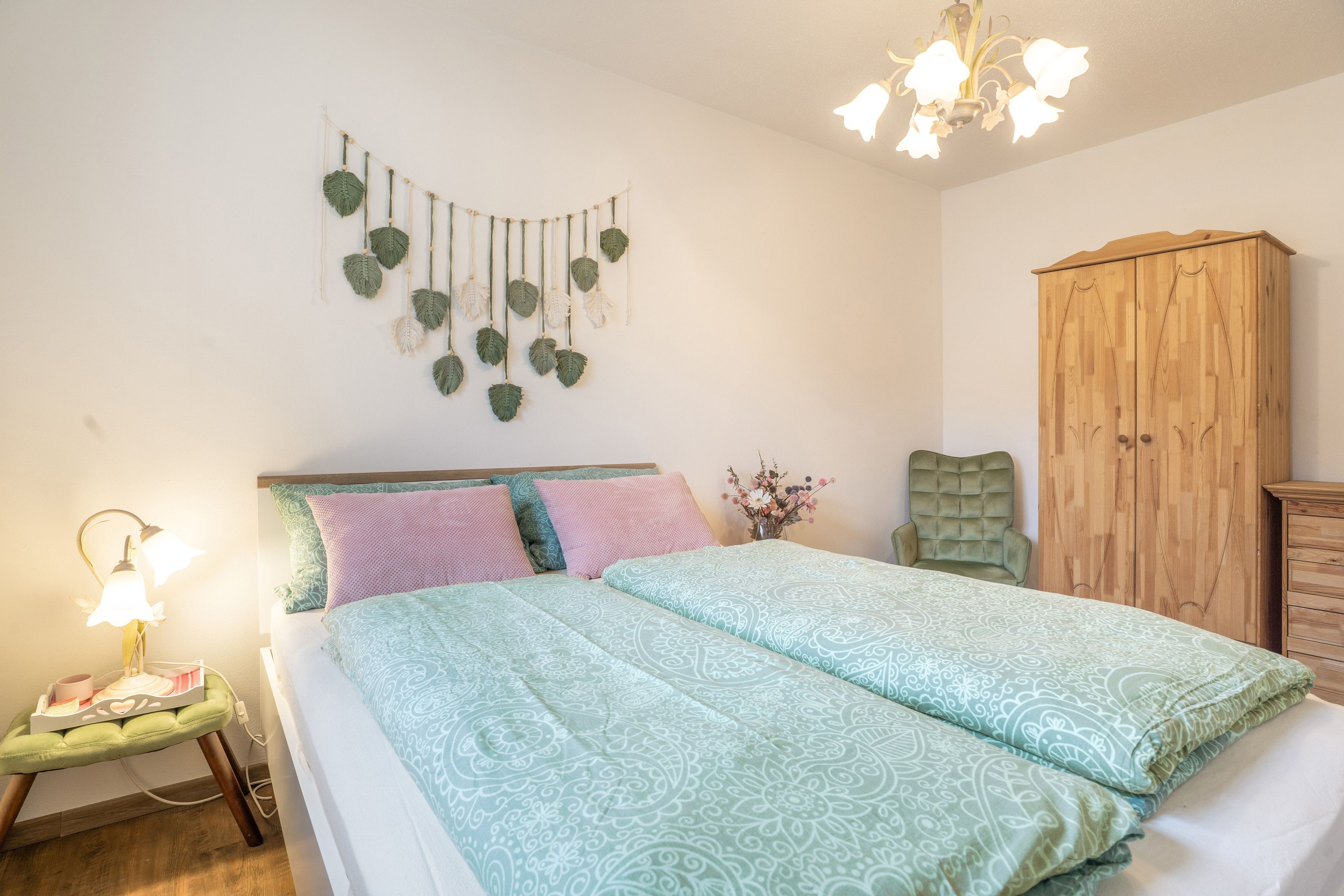 Ein Schlafzimmer mit Bett, Nachttisch, Lampe, Wandgestaltung und einem Kleiderschrank.