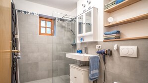 A bathroom with a shower, a sink, a toilet, and a mirror.