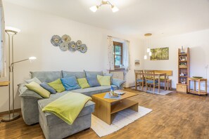 Ein modernes Wohnzimmer mit Sofa, Couchtisch und Essbereich.