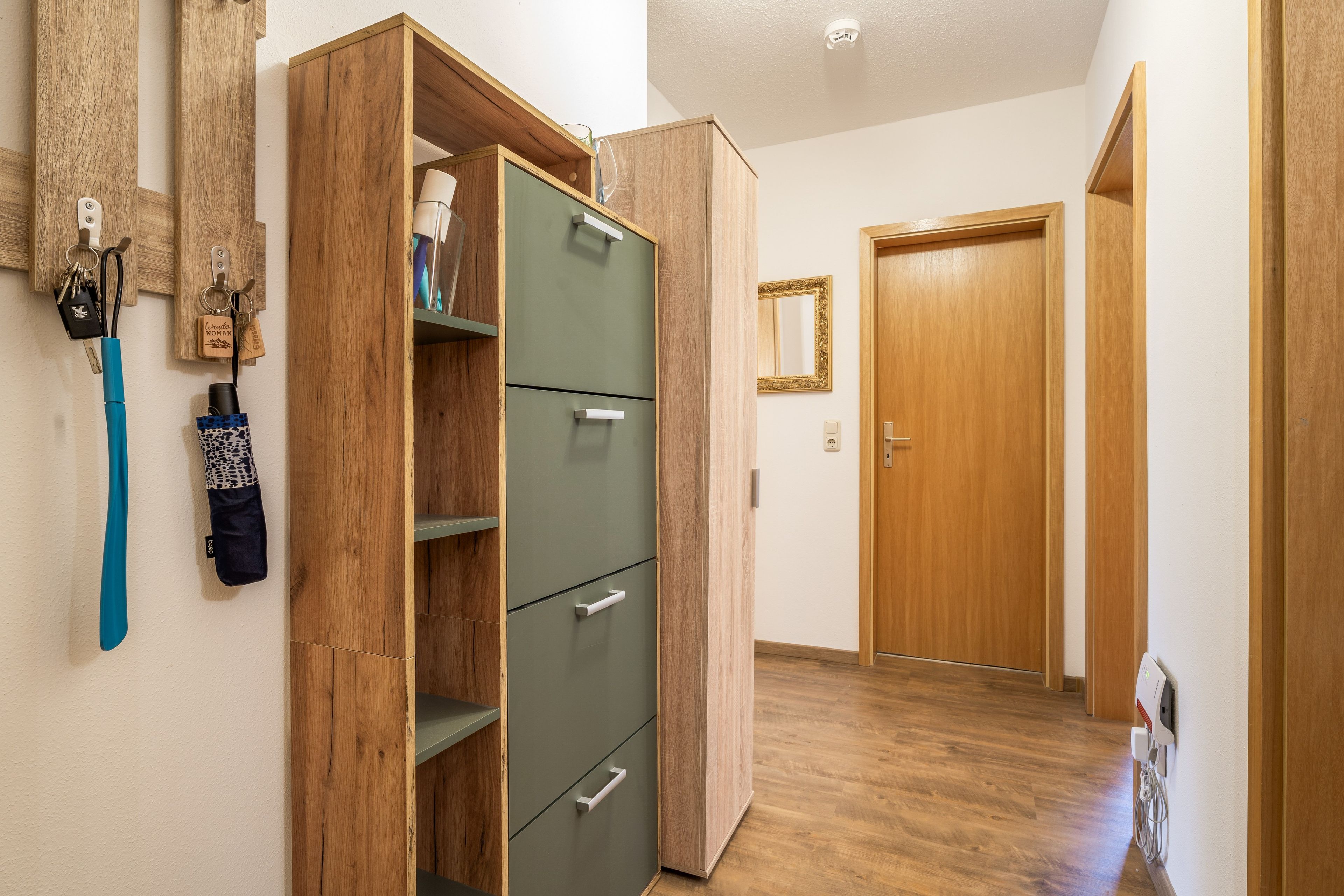 Ein Flur mit einem Holzschrank, einem Spiegel und einer Tür.