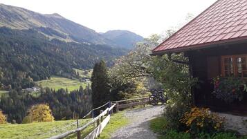 Ein Berggemäuer mit einem Kiesweg, der zu einem Holzzaun mit Blick auf ein Tal führte.